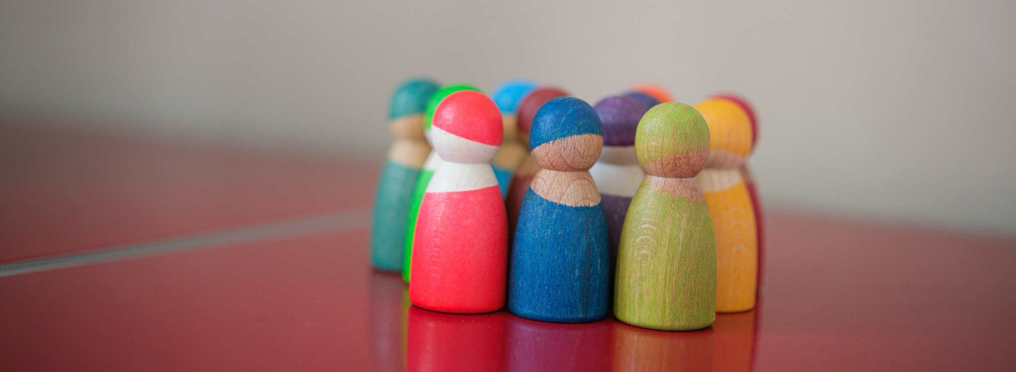 Bunte Holzfiguren stehen auf einer schlichten Oberfläche as Gruppe zusammen.